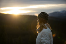 woman in a coat on a mountain at sunset 