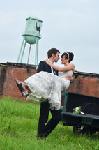 rural setting with a groom carrying his bride 