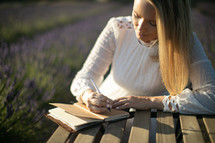 a woman in a field of lavender journaling 