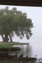man fishing on a lake shore 