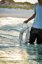 man holding a life ring while standing in the ocean
