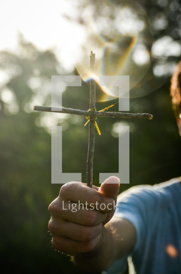 man holding a cross made from sticks