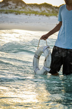 man holding a life ring standing in the ocean