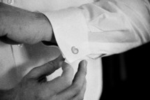 a man fastening a button on his shirt cuff