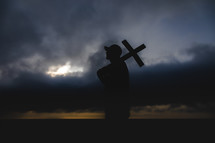 a man standing in a storm holding a cross