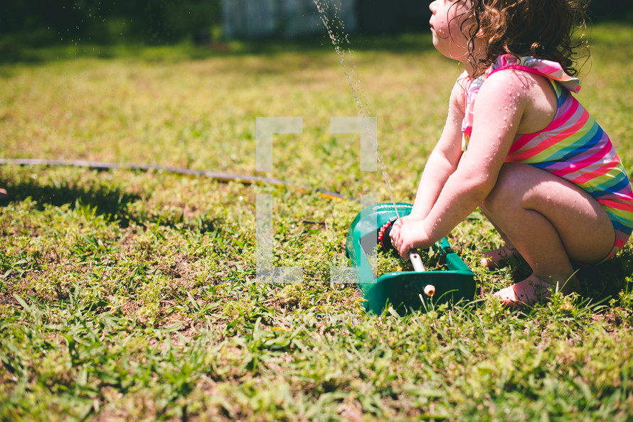 a toddler playing in a sprinkler 