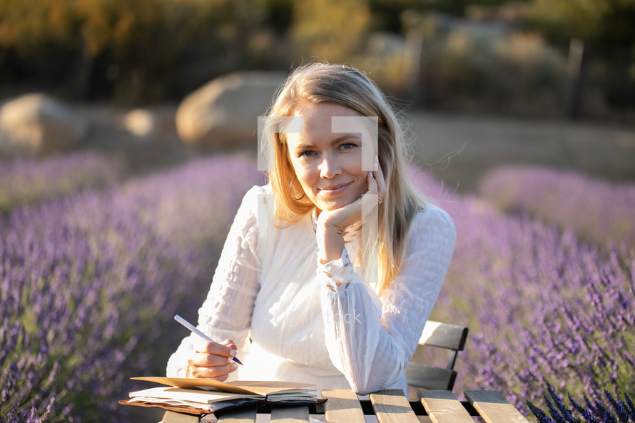 a woman in a field of lavender journaling 