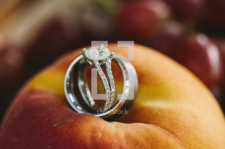 wedding band and engagement ring lying on a peach