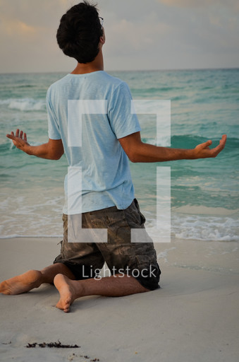 Man kneeling in prayer on a beach — Photo — Lightstock