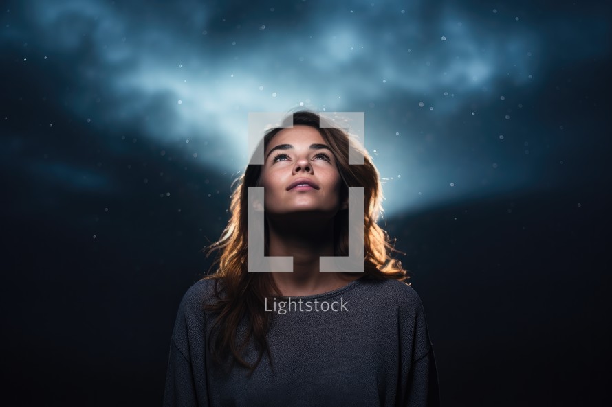 Young woman looking up in the night sky with stars in the background