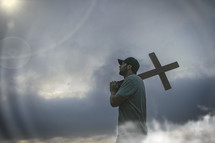 a man standing in a storm holding a cross