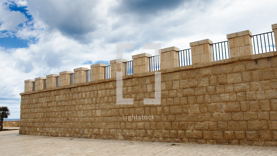 Ancient wall with merlons and sky with clouds background 