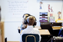 students sitting in a classroom wearing headphones 