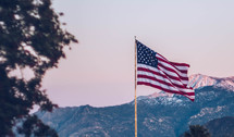 American flag on a flag pole with mountains in the background 
