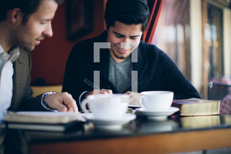 two men reading a Bible and talking over coffee during a Bible study