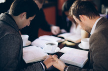 group of people holding hands in prayer at a Bible study