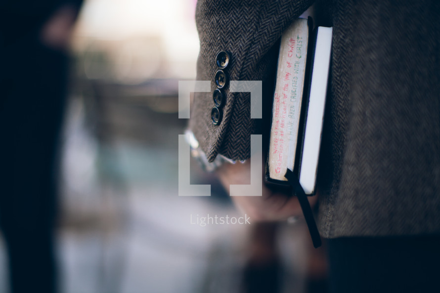 man carrying a Bible and journal at his side heading to a Bible study