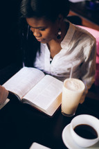 woman reading from a Bible at a Bible study at a coffee house