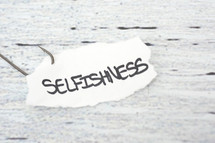 fish hook on paper with the word selfishness 