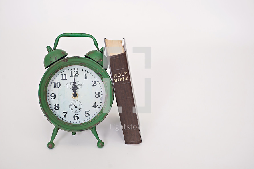 green alarm clock and Bible 