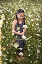 girl in a field holding wildflowers 