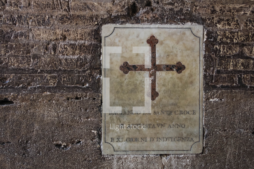 cross placard on a wall at the Colosseum in Rome 