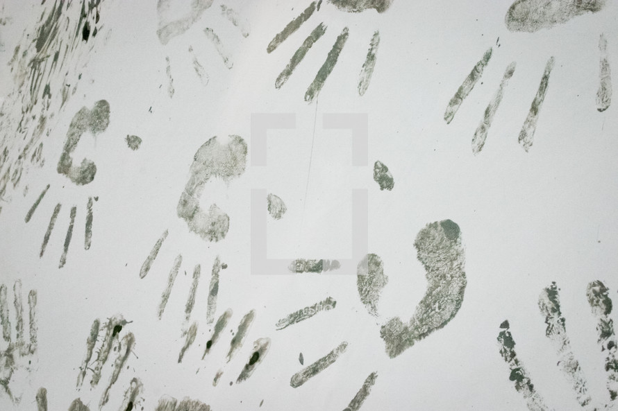 muddy handprints on a white wall 