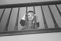toddler looking through stair railings 