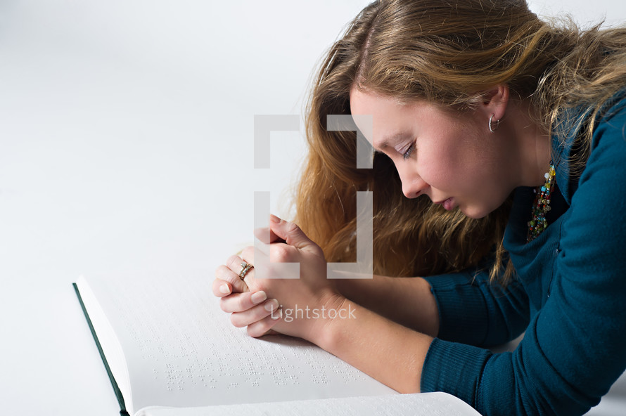 praying hands over a braille Bible 