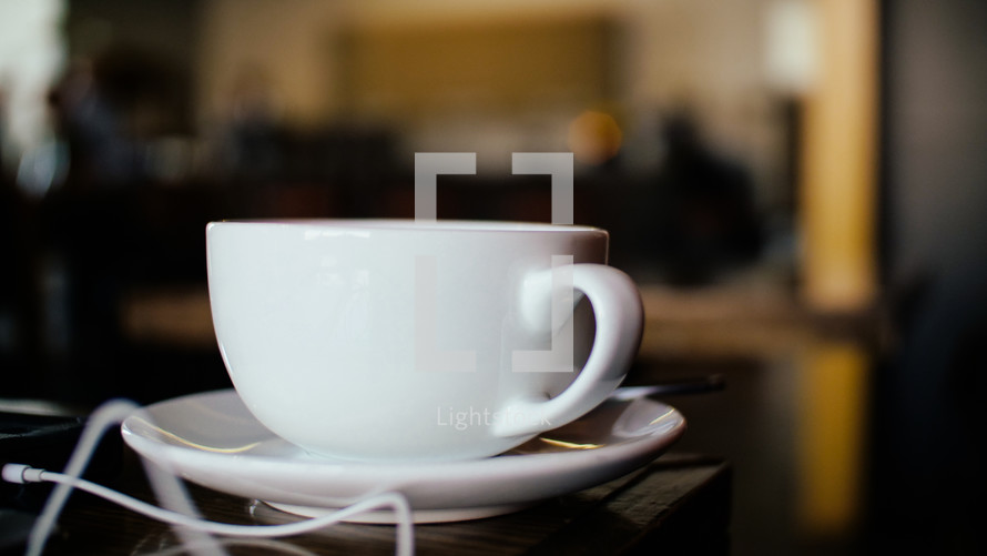 tea cup and saucer and earbuds on a table 
