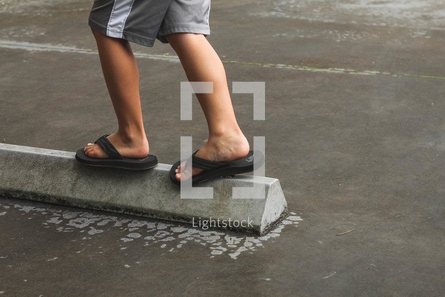 child balancing on concrete barrier 