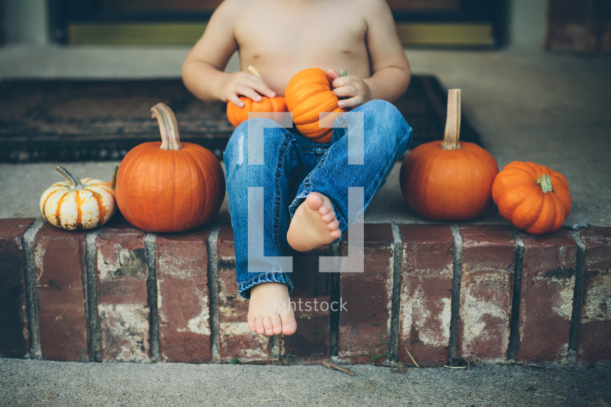 boy sitting on steps holding pumpkins 