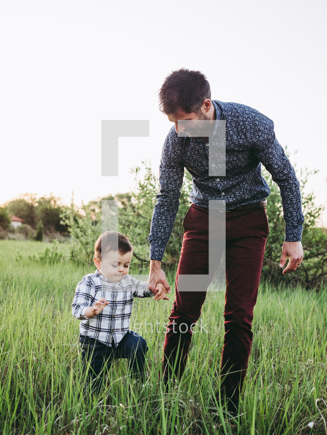 a father walking in a field with his toddler son 