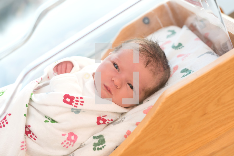 A newborn baby in a hospital crib.