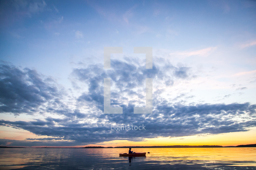 man in a canoe on a lake at sunset 
