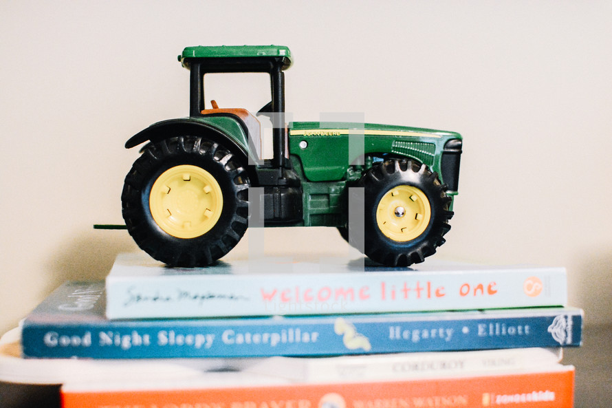 green tractor figurine on a stack of books 