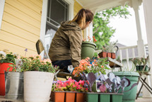 woman planting flower pots on a porch 
