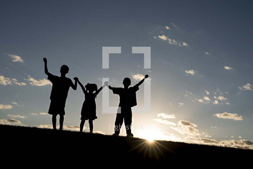 silhouettes of children holding raised hands 