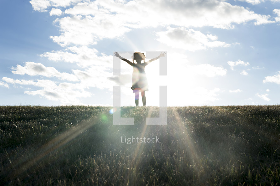 young girl with raised hands and a sunburst 