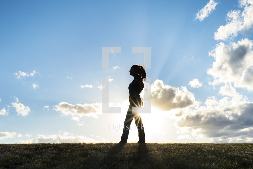 silhouette of a woman and sunburst outdoors 