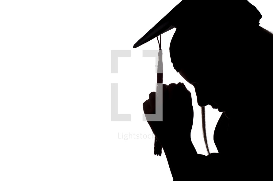 silhouette of a graduate with head bowed and praying hands 