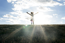 young girl with raised hands and a sunburst 