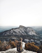 man sitting at the edge of a mountainside 