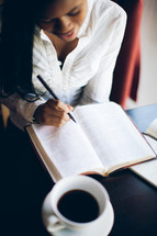 woman reading a Bible and holding a pen