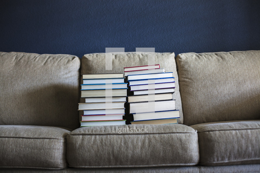 stacked books on a couch 