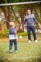 father and son playing soccer outdoors 