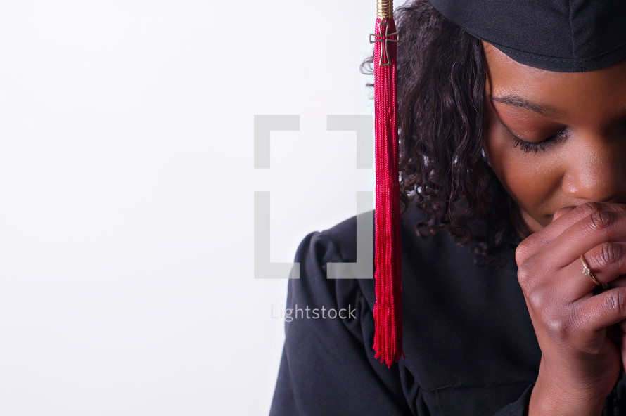 An African American graduate with praying hands 