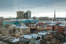 water drops on a window overlooking the city below 