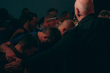 congregation and minister praying during a worship service 