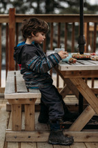 boy eating muffins on a back deck 